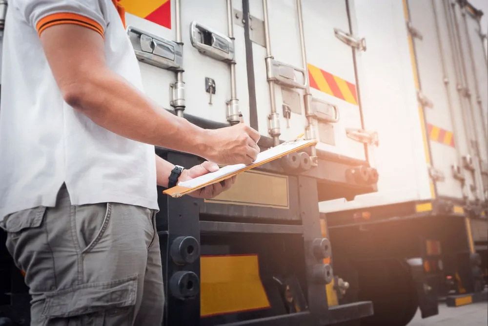 A Person With Clipboard Inspecting the Back of a Truck — Hines Refrigerated Transport Pty Ltd in Tamworth, NSW