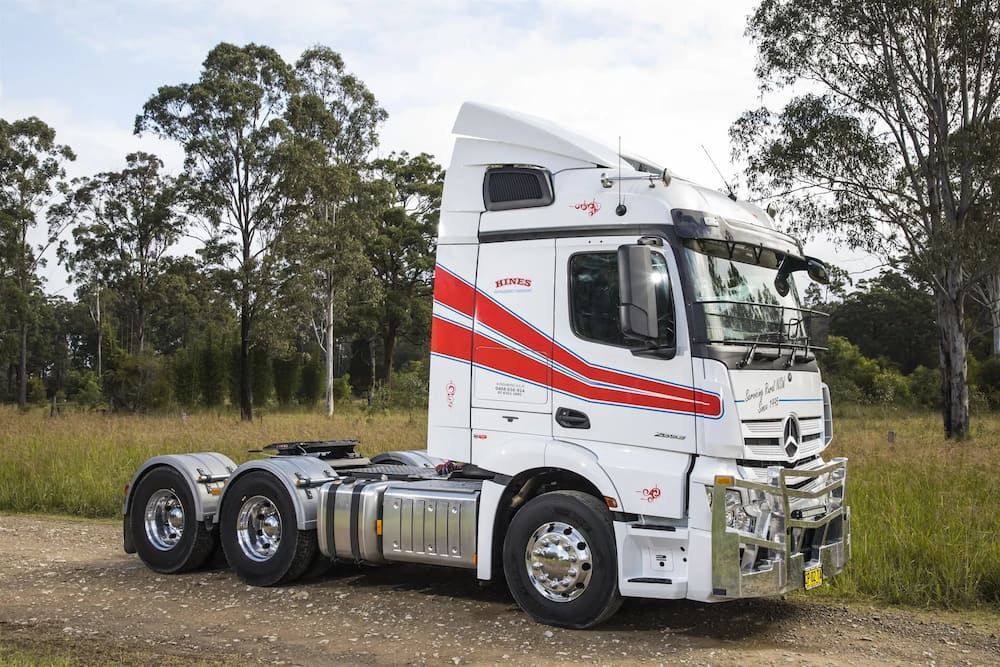 White Semi-truck With Red Graphic, Parked on a Dirt Road in a Field — Hines Refrigerated Transport Pty Ltd in Kundabung, NSW