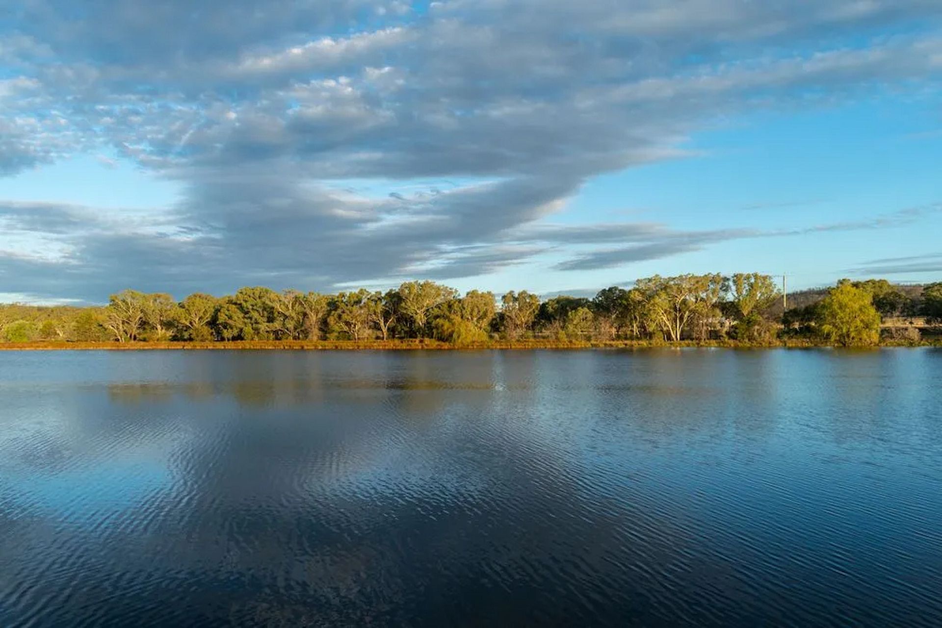 Calm Blue Lake With Trees on the Far Bank Under a Cloudy Sky — Hines Refrigerated Transport Pty Ltd in Inverell, NSW