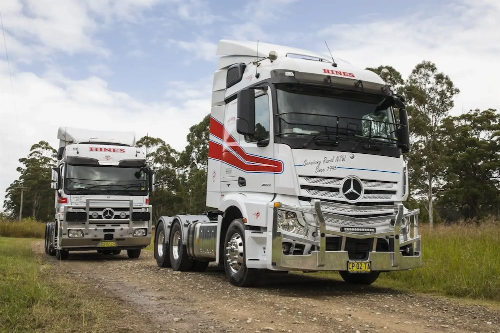 Two White Semi-trucks on a Dirt Road, One in Front of the Other — Hines Refrigerated Transport Pty Ltd in Kundabung, NSW