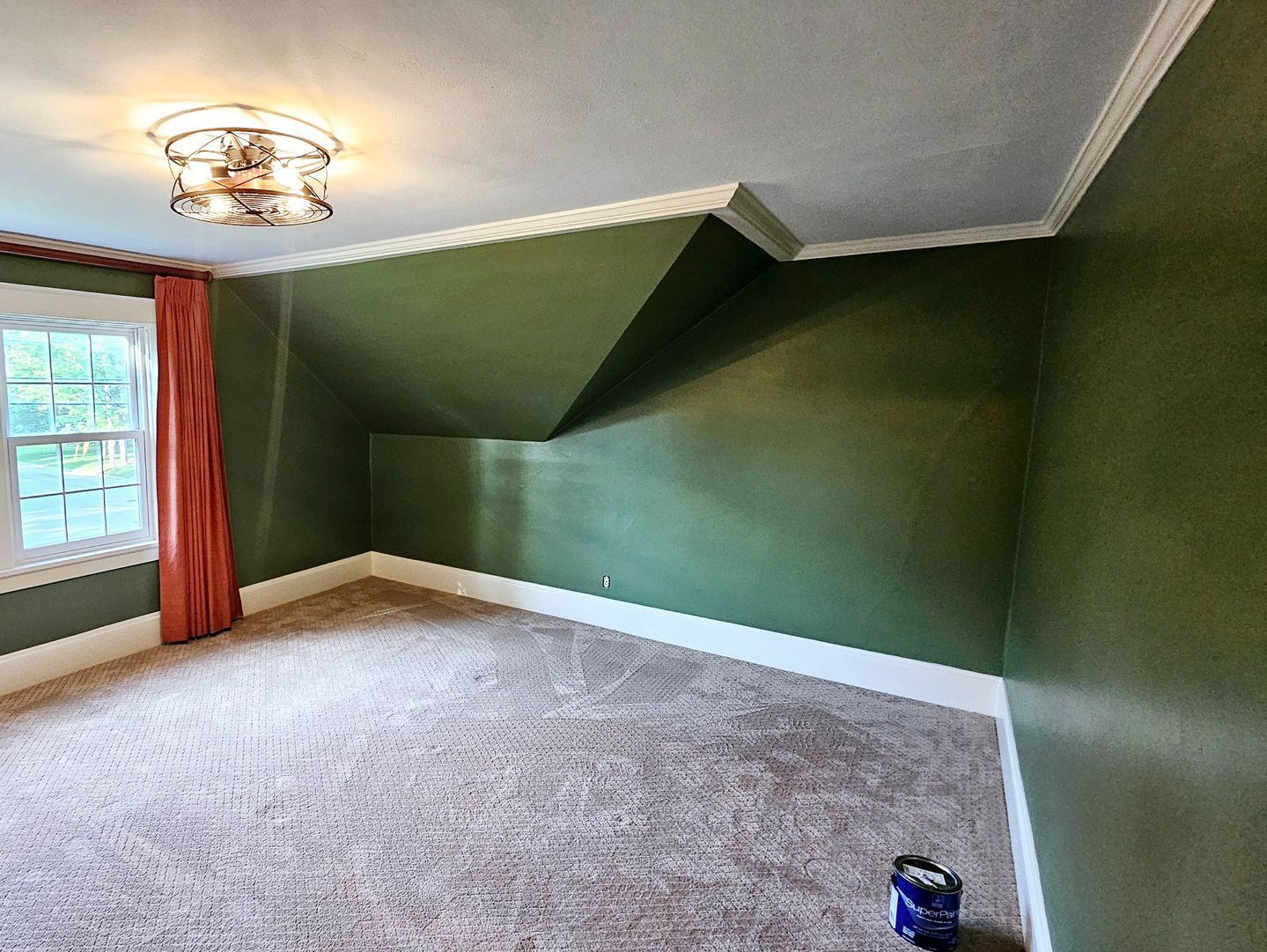 An empty room with green walls and a window.
