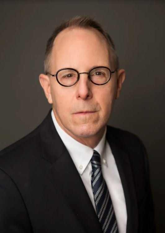 A man in a suit and tie is wearing glasses