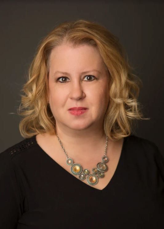 A woman is wearing a necklace and a black shirt.