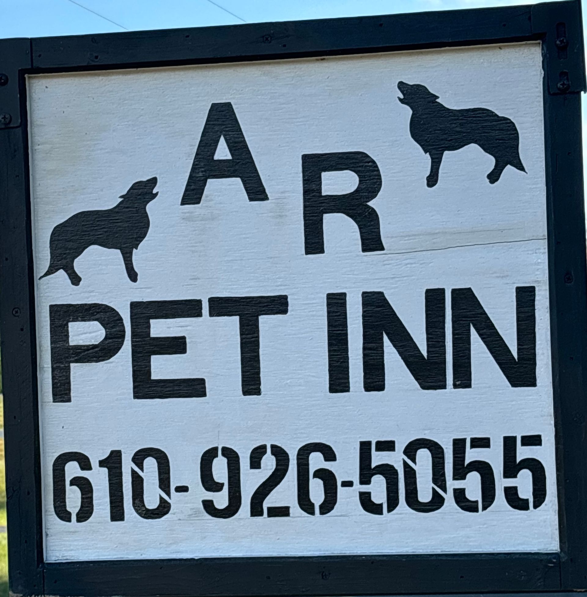 A sign for a pet inn with two dogs on it