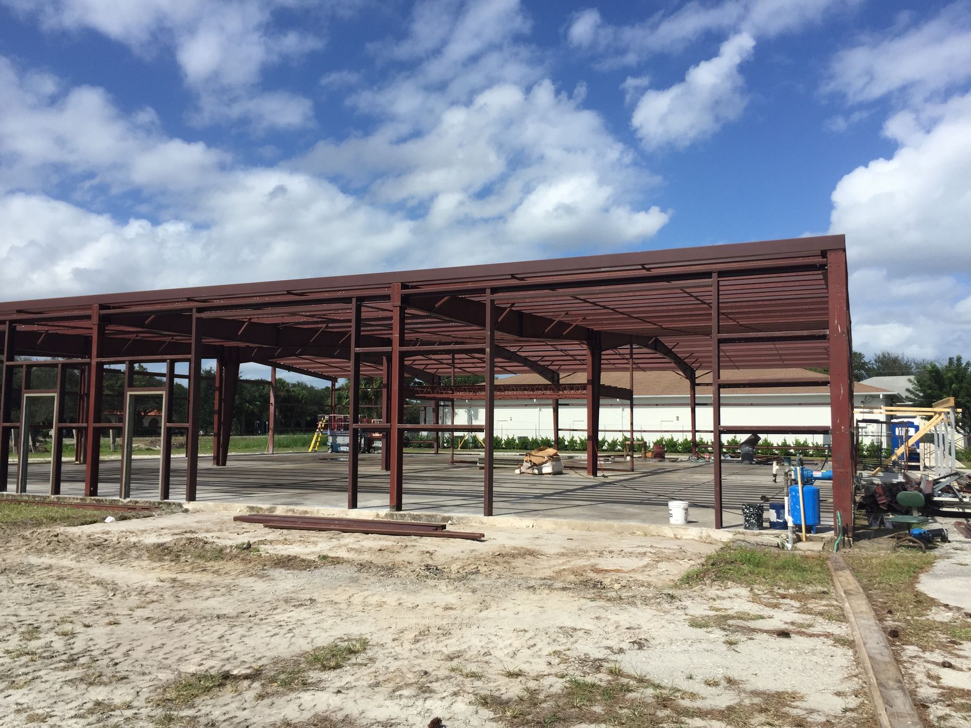 A large metal structure is being built in a dirt field