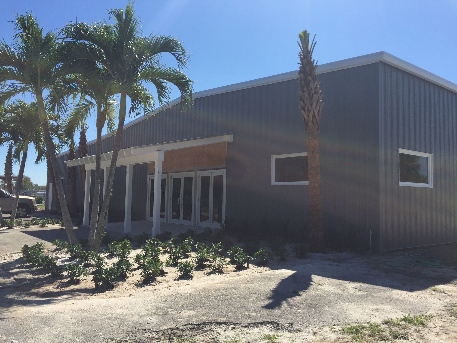 A large gray building with palm trees in front of it.