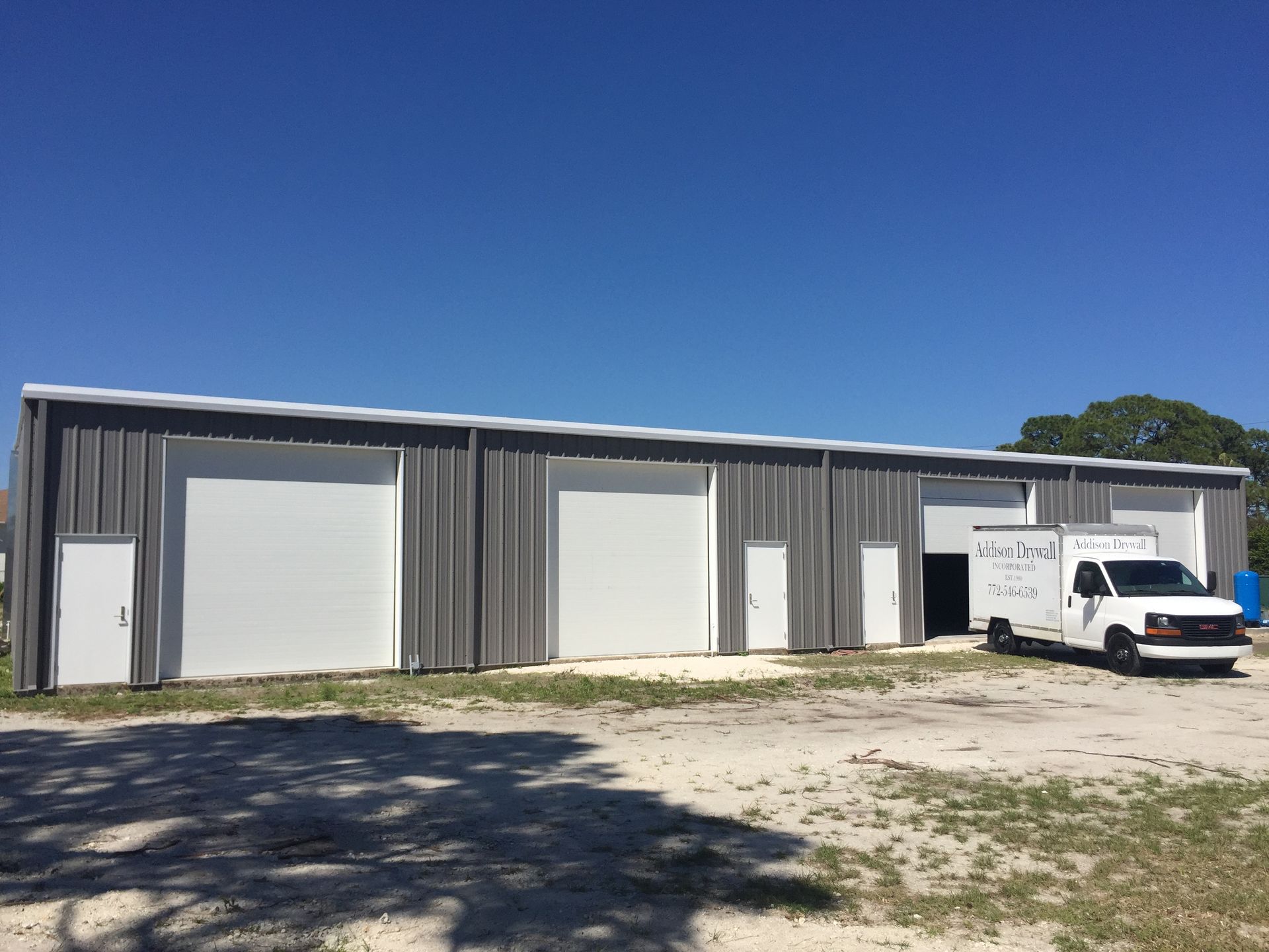A white van is parked in front of a large building.
