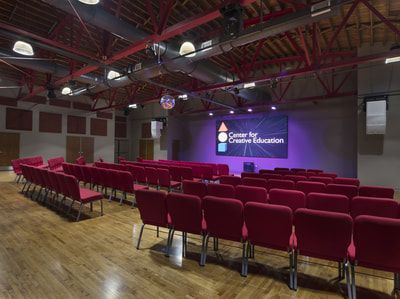 A large auditorium filled with red chairs and a large screen.