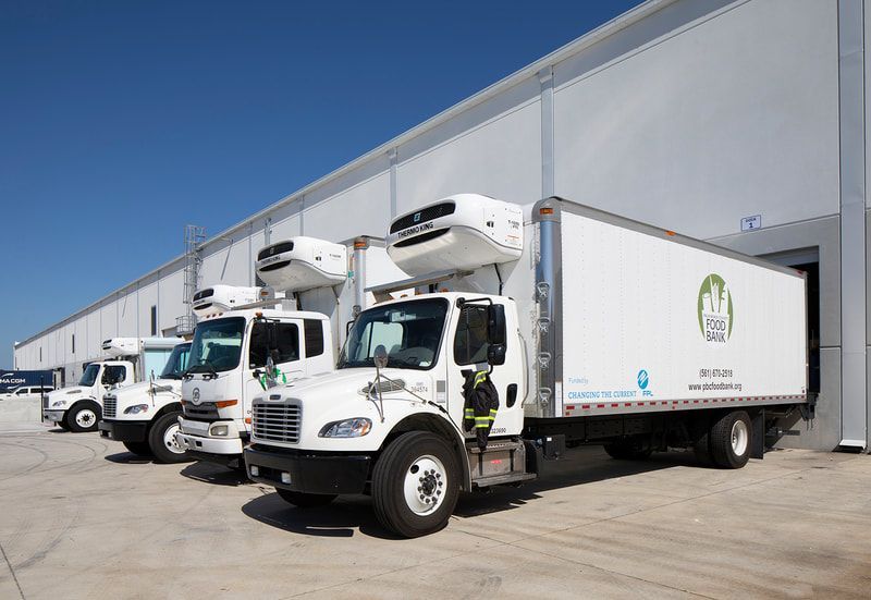 A row of white trucks are parked in front of a building.