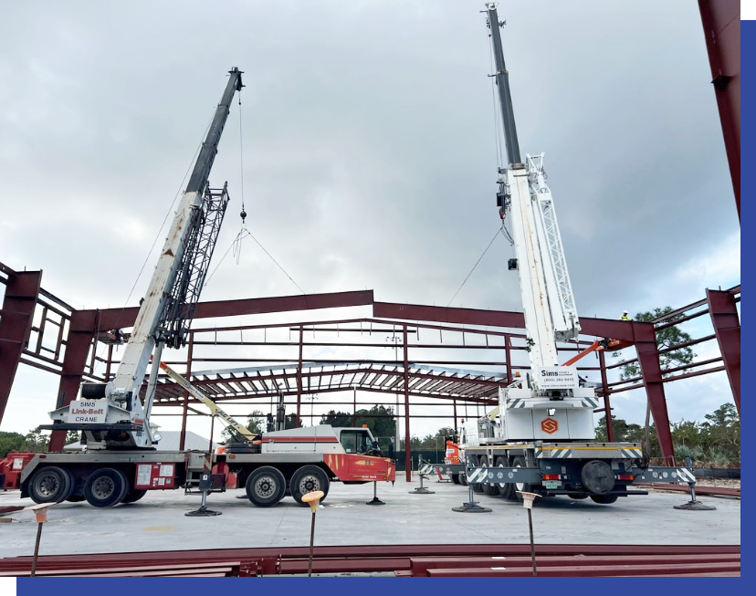 Two cranes are working on a building under construction.