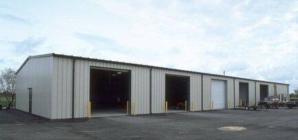 A large metal building with a lot of doors and a truck parked in front of it.