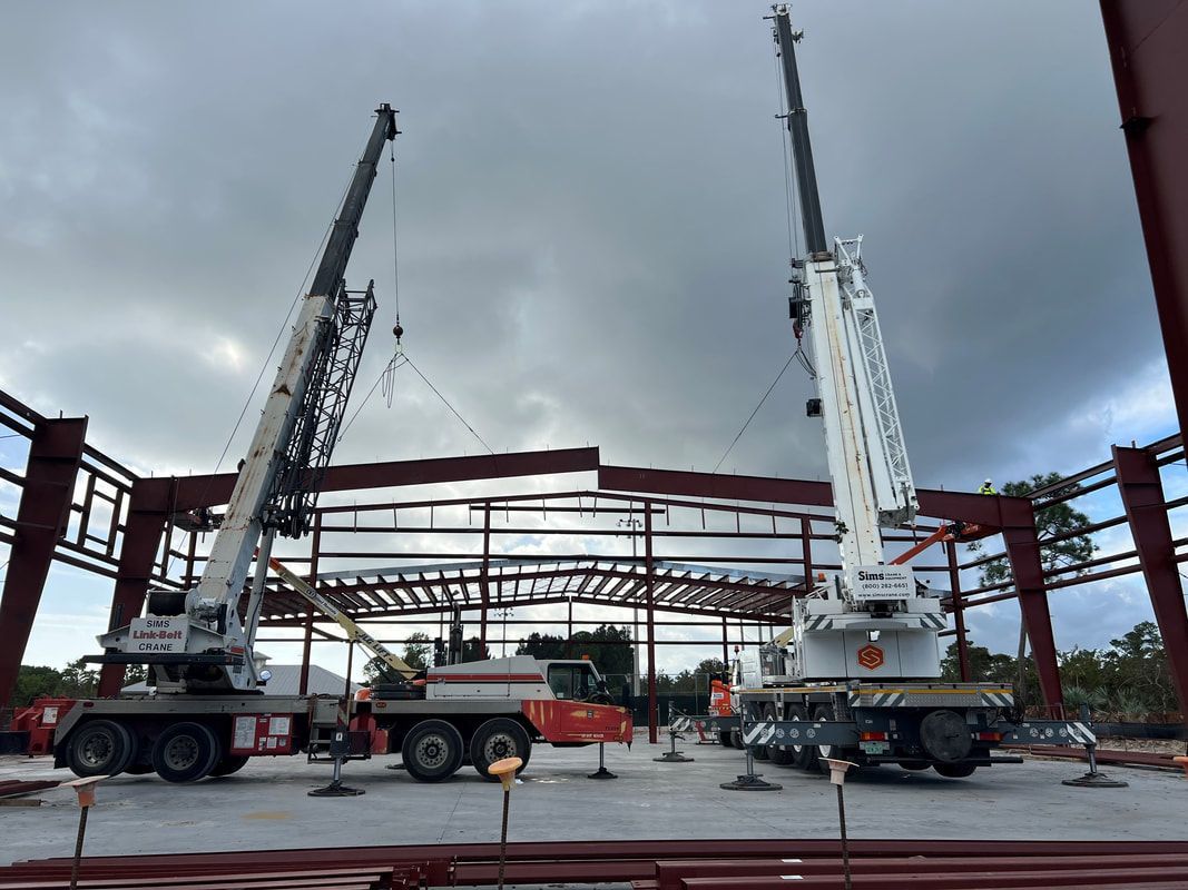 Two cranes are working on a building under construction.
