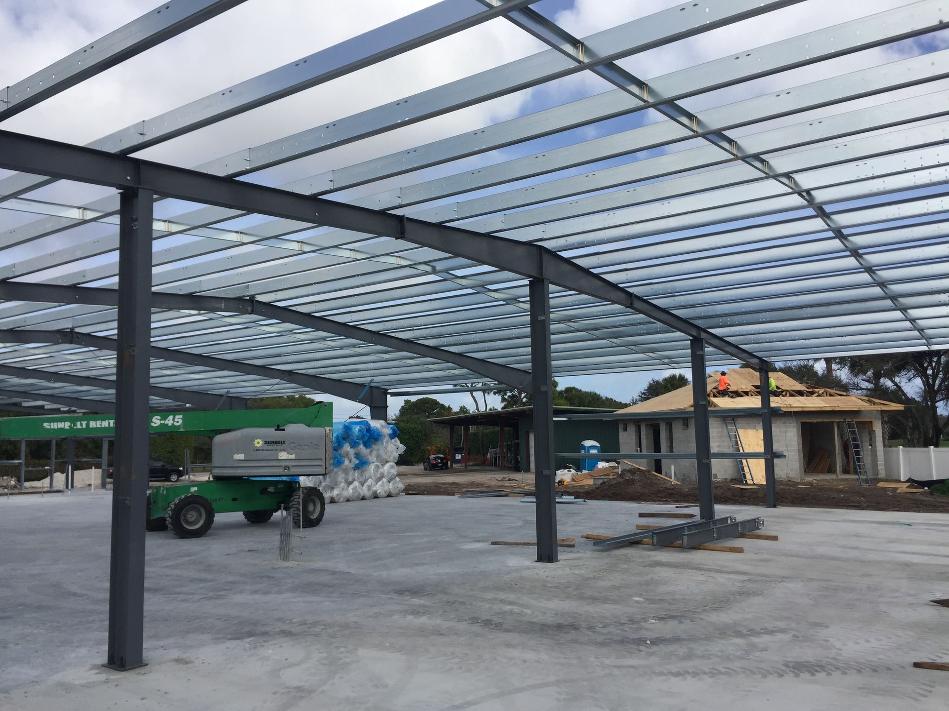 A large metal structure is being built in a parking lot.