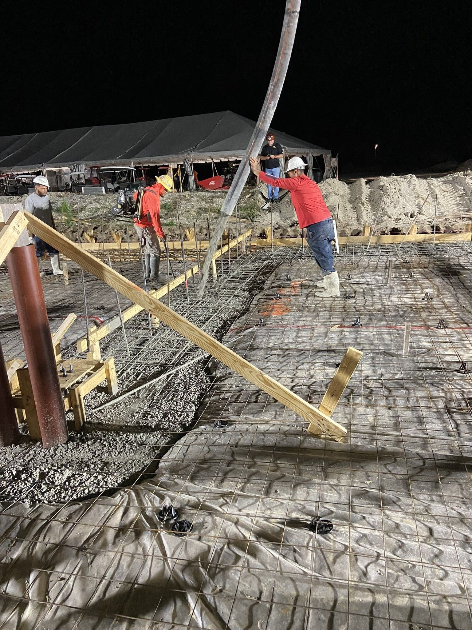 A large metal structure is being built in a parking lot.