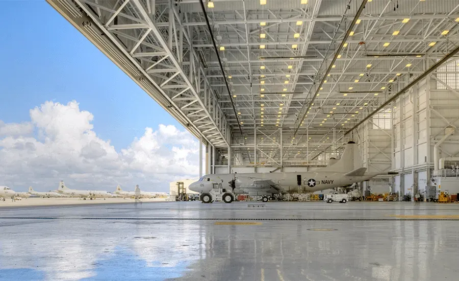 An airplane is parked in a hangar with the roof open.