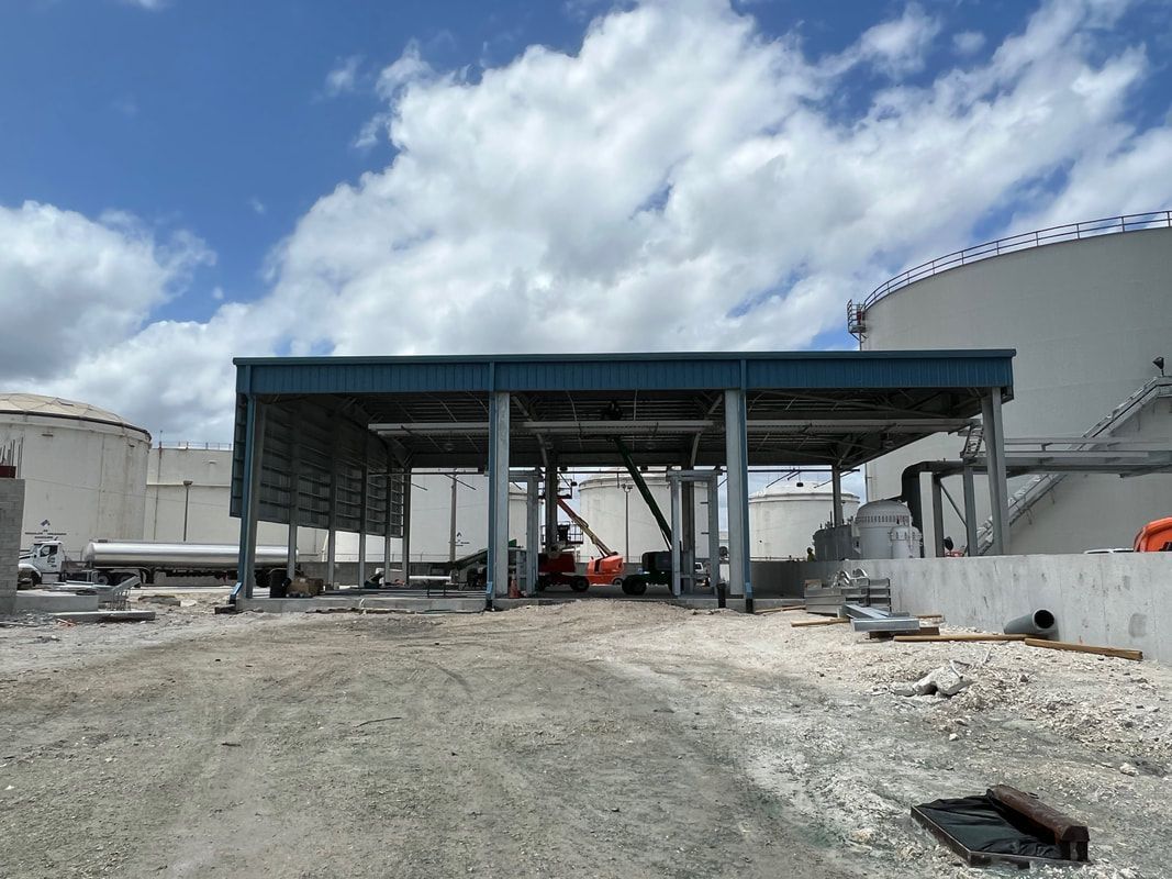 A large building is being built next to a large tank.
