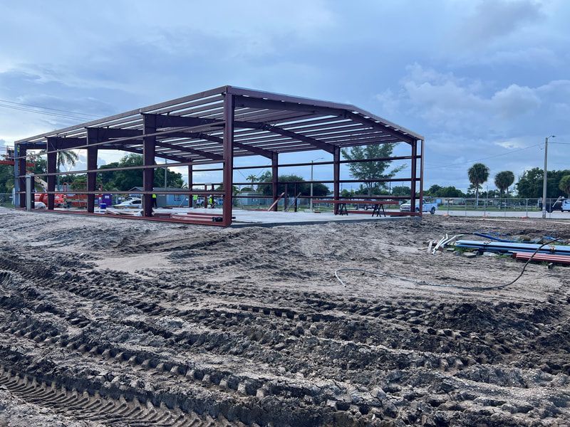 A large metal structure is being built in a dirt field.