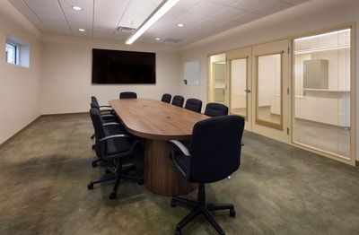 A conference room with a long table and chairs and a flat screen tv.