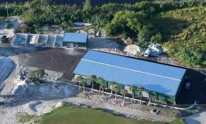 An aerial view of a large building with a blue roof surrounded by trees.