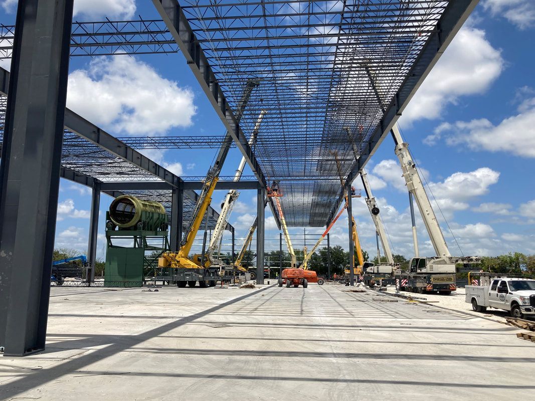 A large building under construction with a lot of cranes and trucks.