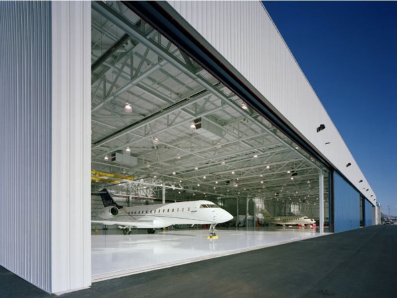 An airplane is parked in a hangar with the doors open