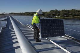 A man is installing solar panels on the roof of a building.