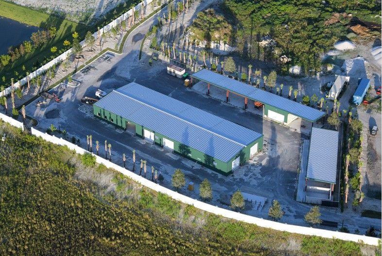 A green building is being built on a dirt field.