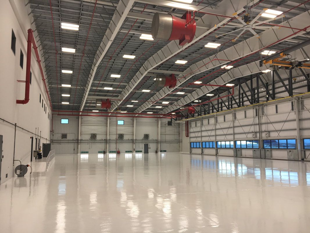 A large empty warehouse with a lot of lights on the ceiling.