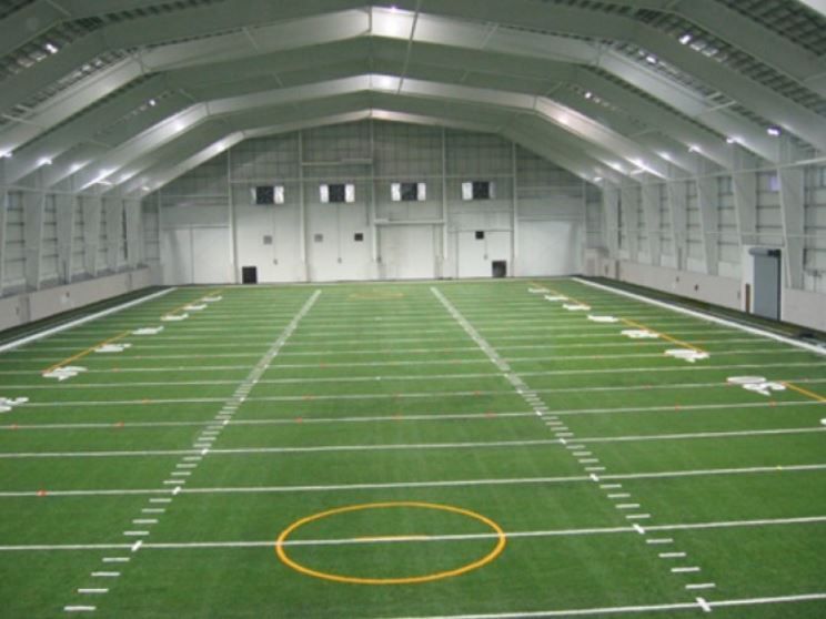 An indoor football field with a yellow circle in the middle