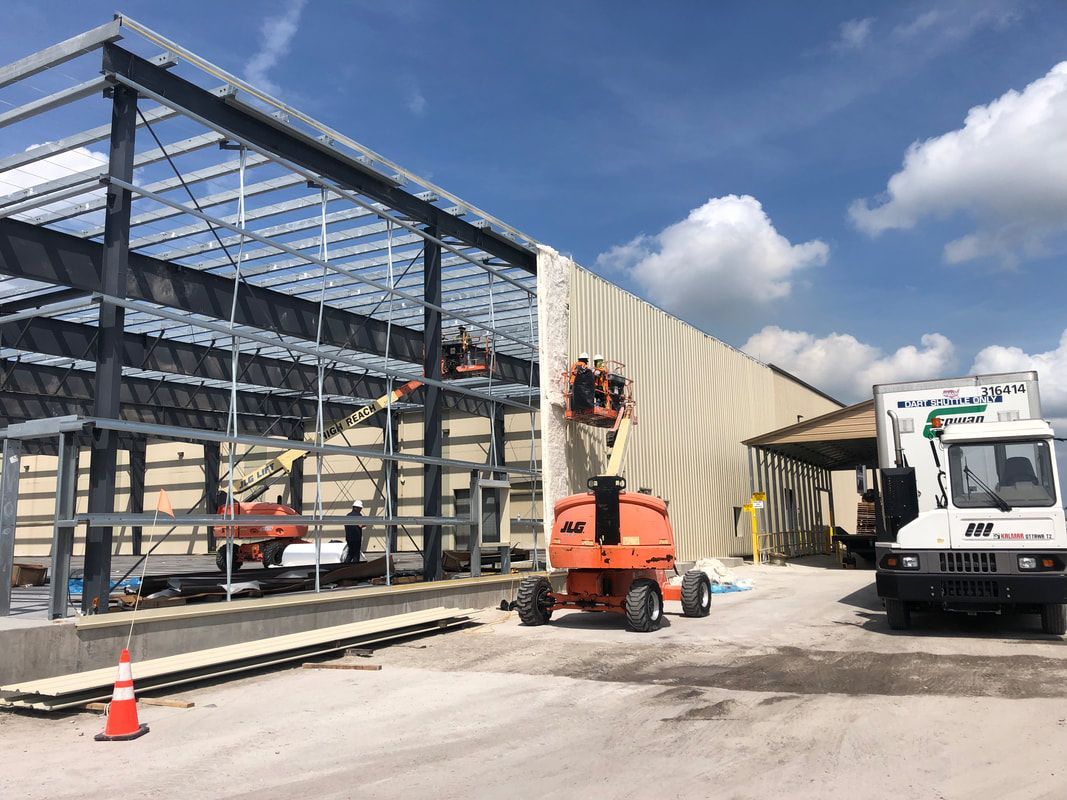 A large building is being built and a truck is parked in front of it.