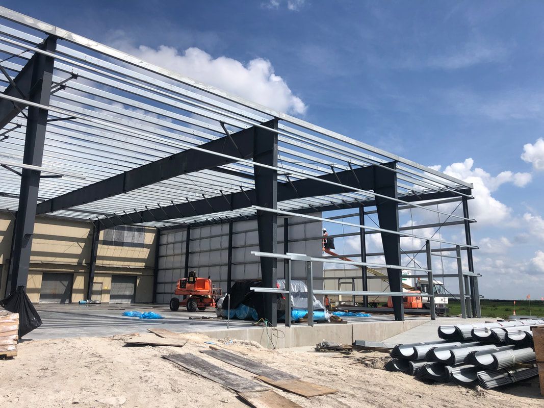 A large metal structure is being built in the middle of a dirt field.