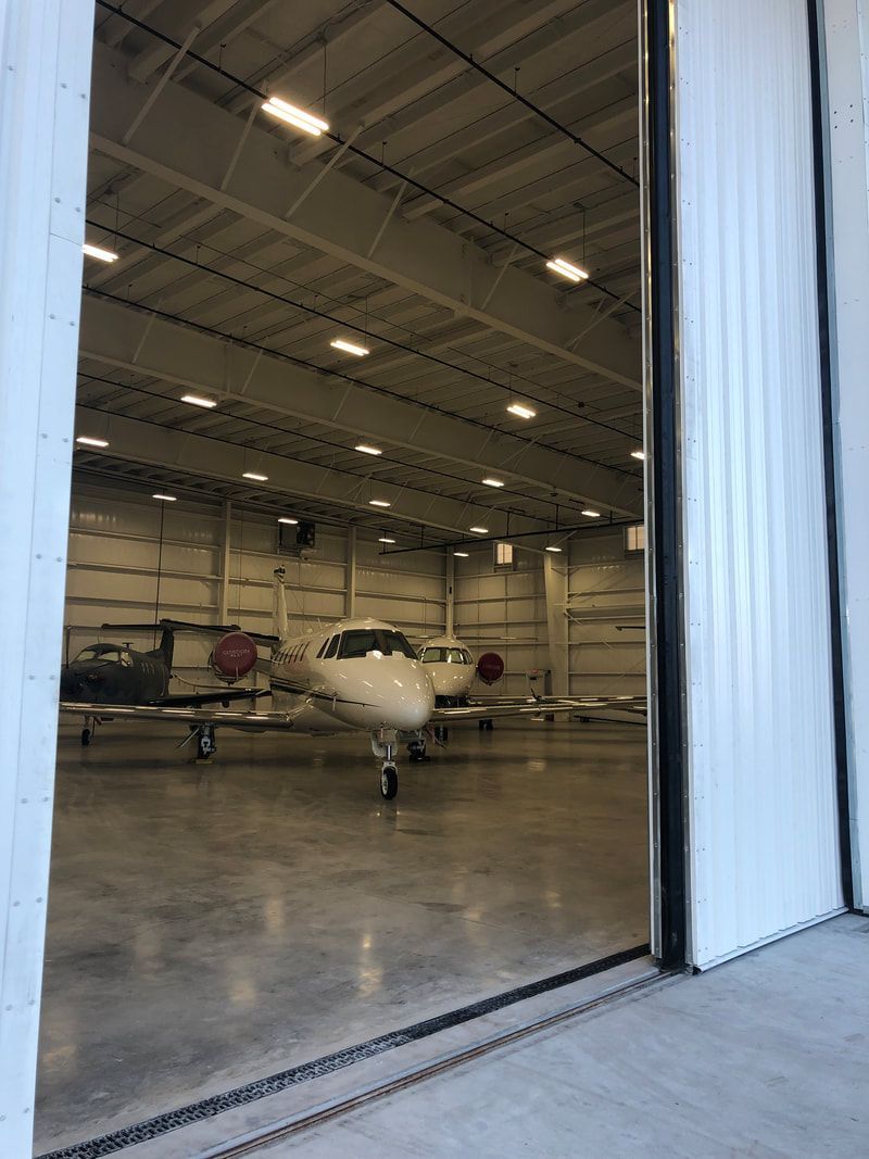 A plane is parked in a hangar with the door open.