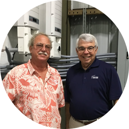 Two men are standing next to each other in a circle in front of electrical equipment