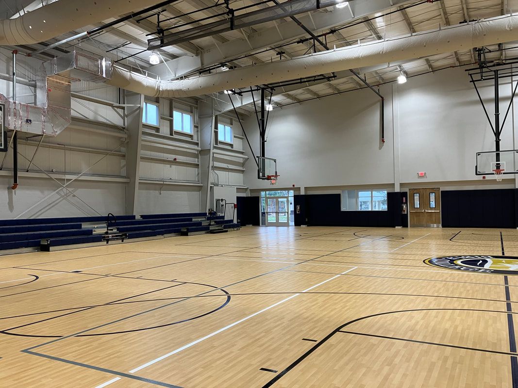 A large indoor basketball court with a wooden floor and a basketball hoop.