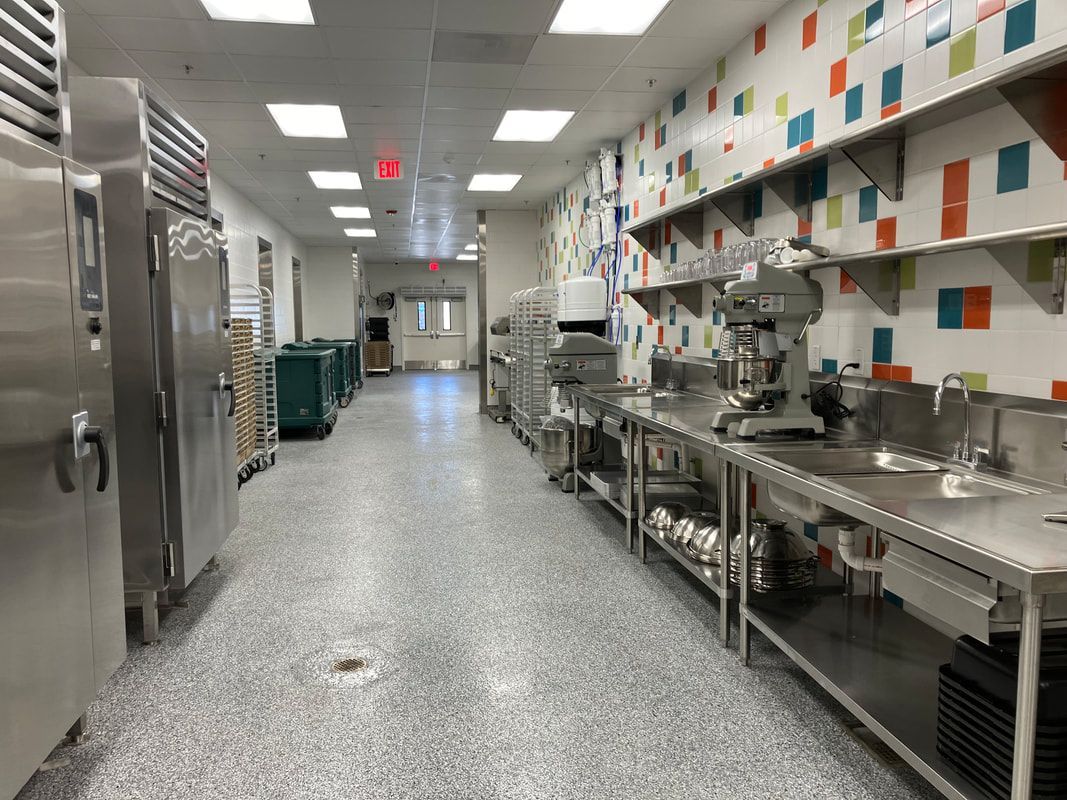 A kitchen with a lot of stainless steel appliances and a long hallway.