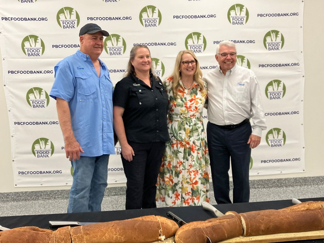 A group of people are posing for a picture in front of a large piece of bread.