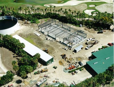 An aerial view of a construction site with a golf course in the background