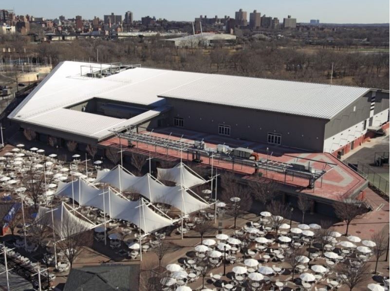 An aerial view of a large building with tables and umbrellas in front of it