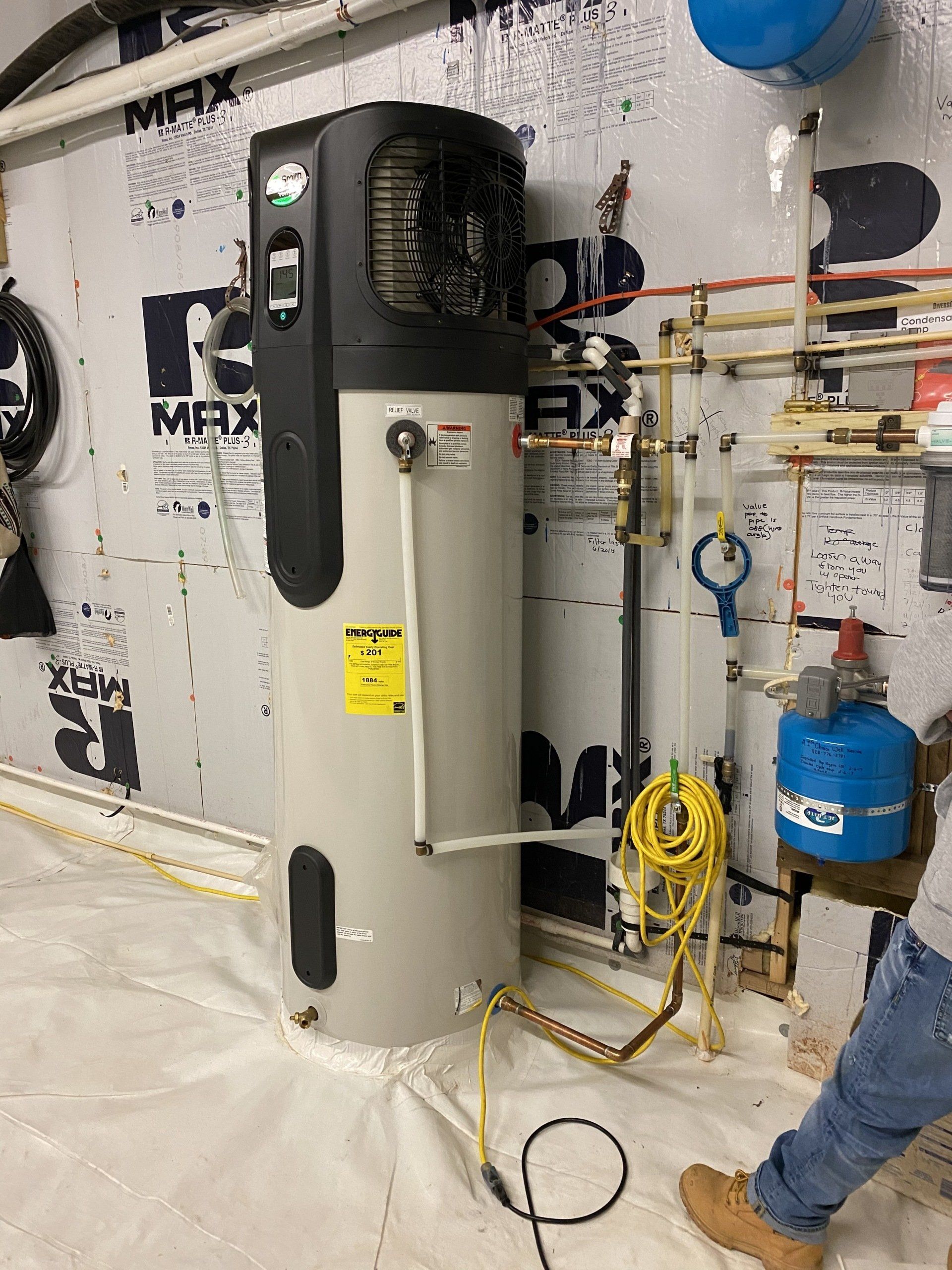 A man is working on a water heater in a basement.