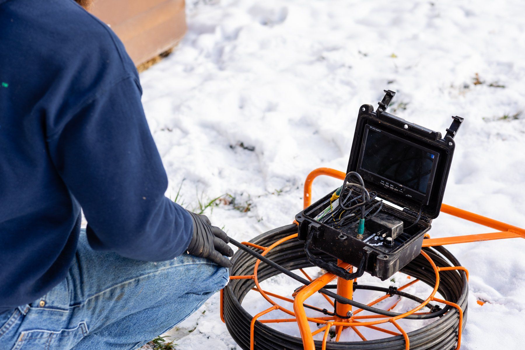 A man is kneeling down in the snow next to a camera.