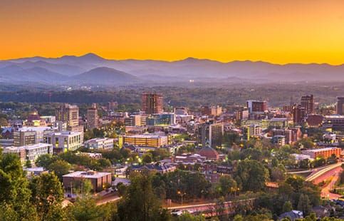 An aerial view of a city with mountains in the background at sunset.