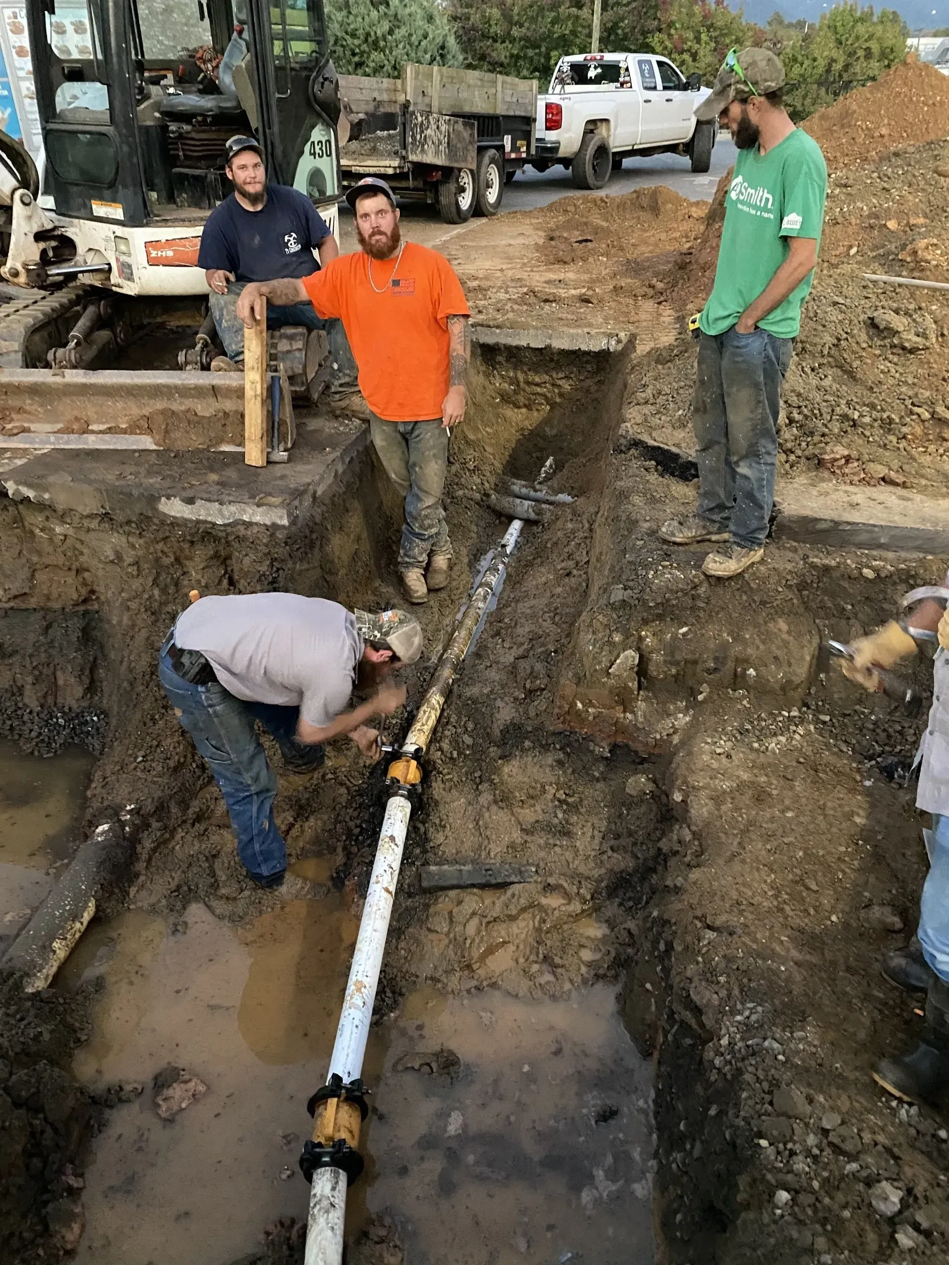 A group of men are working on a pipe in the dirt.
