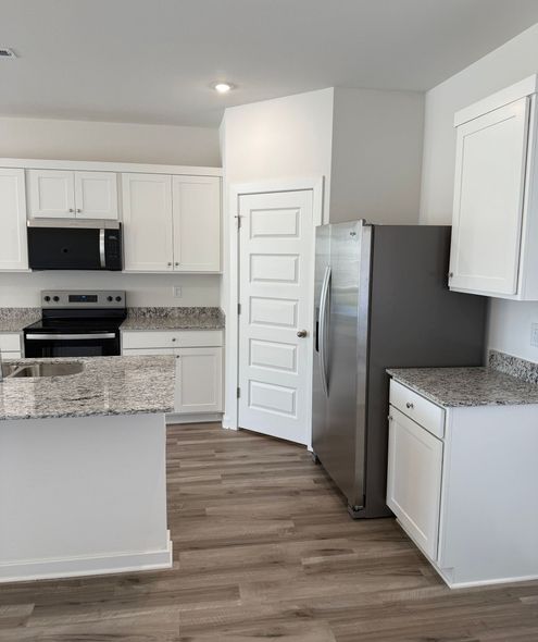 Photo of a kitchen with contemporary appliances and a door to a pantry