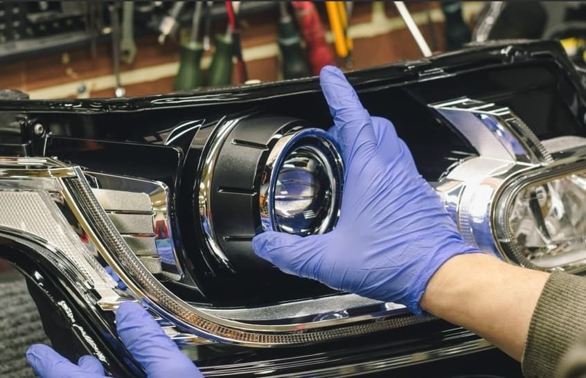 A Person Wearing Blue Gloves Is Working On A Car Headlight — A.G Auto Electrical & Air-Conditioning In Hidden Valley, QLD