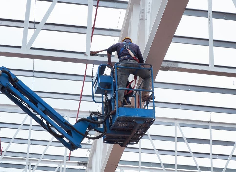 A Man Is Sitting On A Lift Working On A Building — A.G Auto Electrical & Air-Conditioning In Hidden Valley, QLD