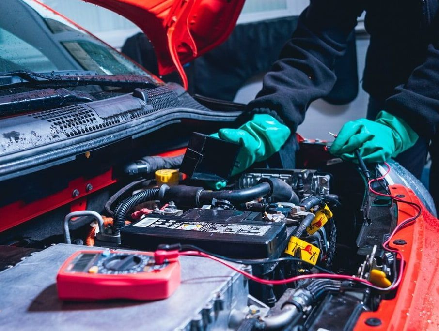 A Man Is Working On The Engine Of A Red Car — A.G Auto Electrical & Air-Conditioning In Hidden Valley, QLD