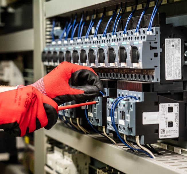 A Person Wearing Red Gloves Is Working On An Electrical Panel — A.G Auto Electrical & Air-Conditioning In Hidden Valley, QLD