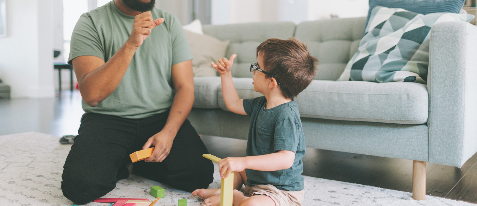 A man and a boy are playing with toys on the floor in a living room.