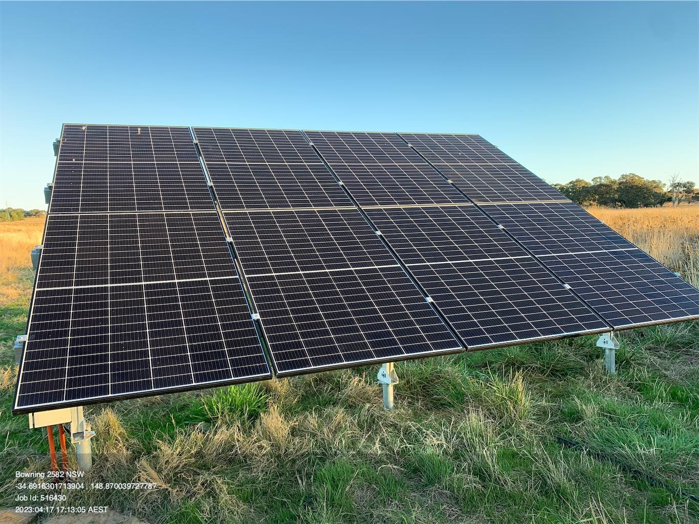 Large solar panel array in a grassy field under a clear blue sky