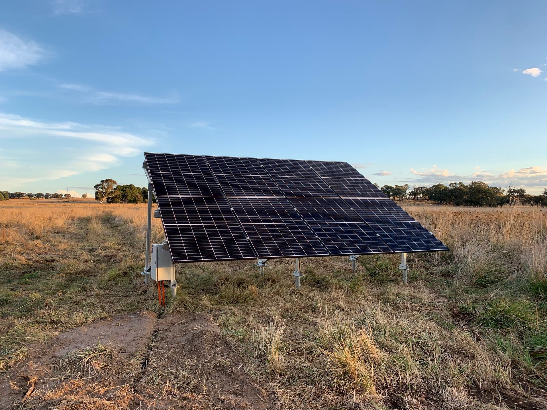 Solar panel array in a grassy field under a clear blue sky.